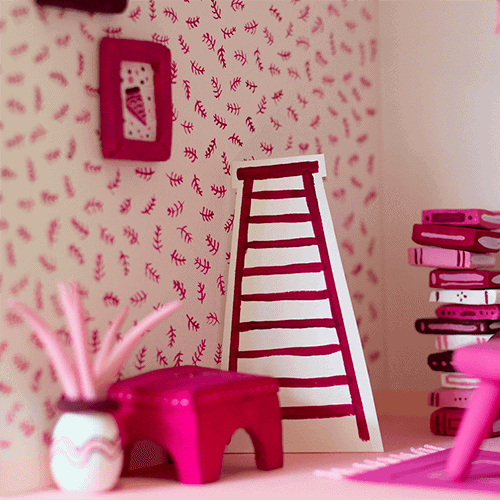 A 3D handmade model of a pink living room made with painted clay and painted paper.