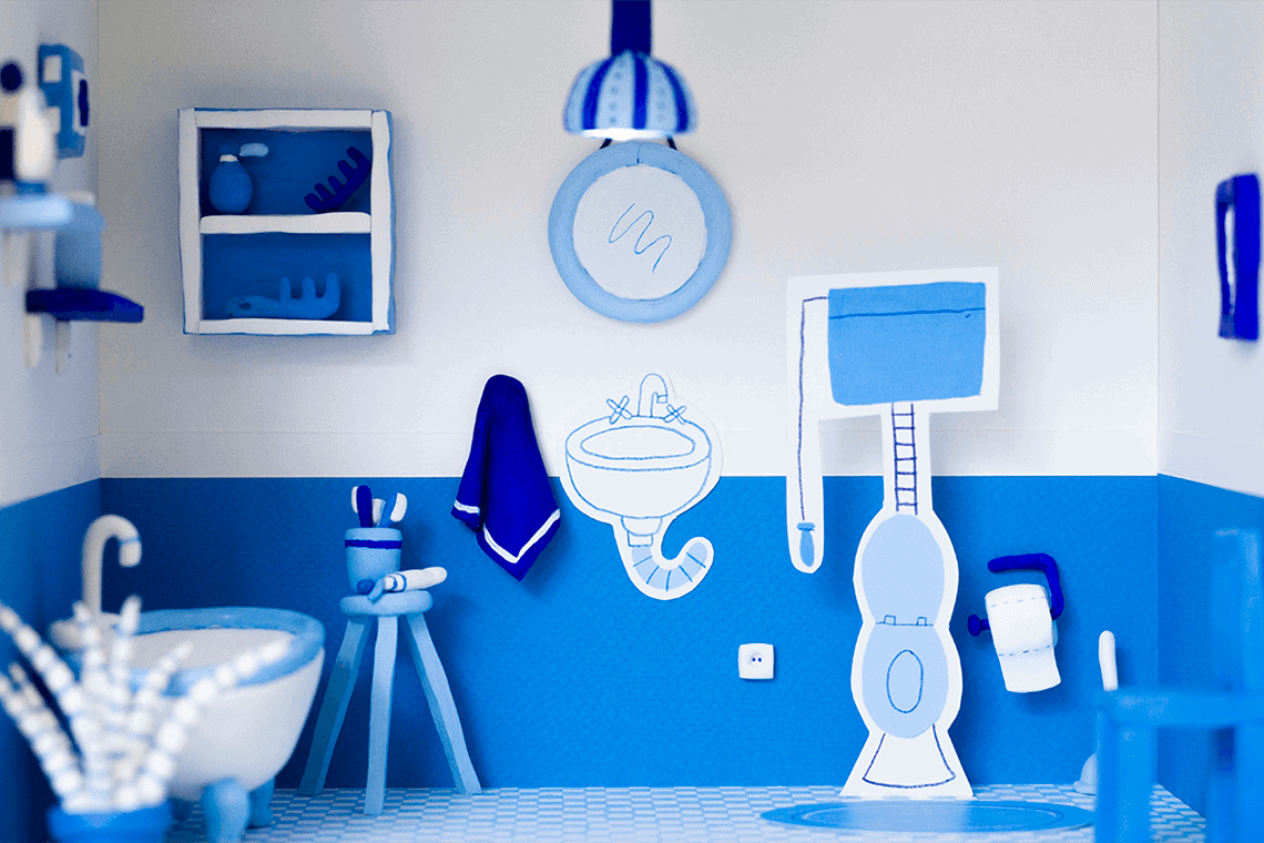 A 3D handmade model of a blue bathroom made with painted clay and painted paper.
